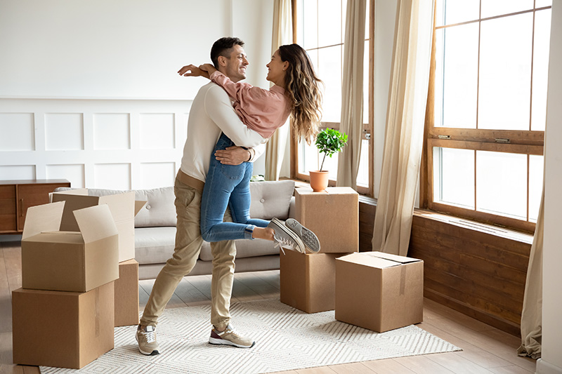 A happy couple celebrating in their new home surrounded by moving boxes